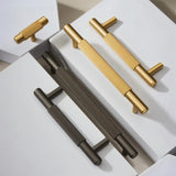 "Modern brass cabinet knobs and pull handles with a textured, knurled grip in gold and gray finishes."