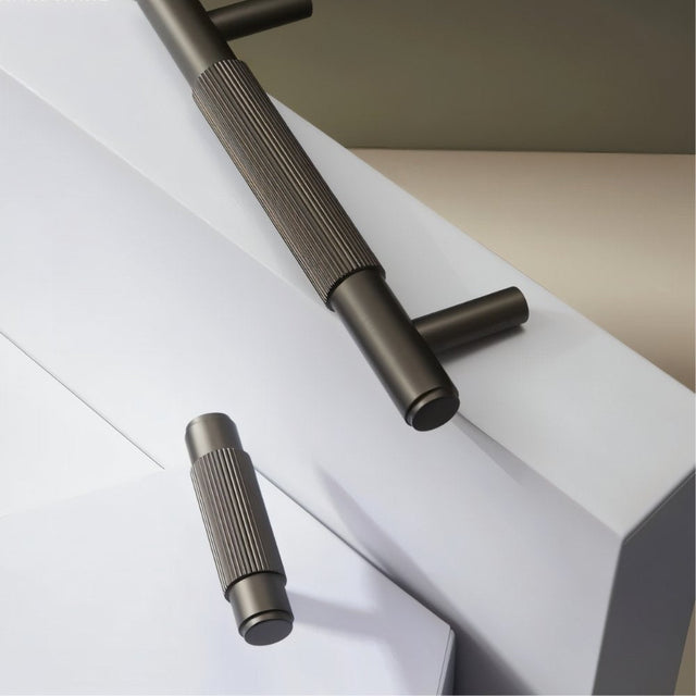 "Close-up of modern brass knurled pull handles and knobs on a white and gray background."