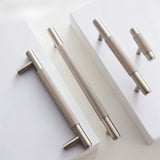"Modern brass knurled pull handles and knobs for cabinets and drawers on a white background."