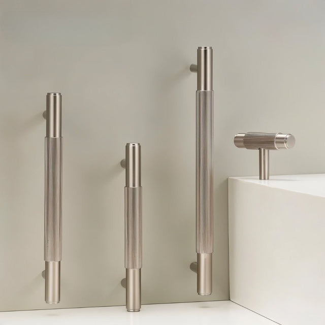 "Modern brass knurled T-bar pulls and knobs for cabinets and drawers on a gray background."