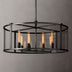 Black metal cylindrical chandelier with clear glass panels and warm Edison-style bulbs against a gray background.