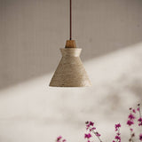 Menra Pendant Light with travertine and wood materials, suspended in a softly lit room with floral accents for cozy ambiance.
