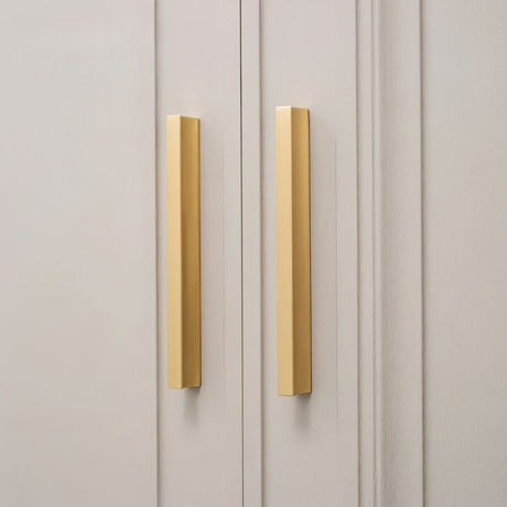 "Pair of sleek geometric brushed brass pull bars on modern gray cabinets."