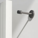 "Sleek, cylindrical door stop in brushed nickel zinc-alloy with extended arm, wall-mounted to prevent a door from hitting the wall in a modern interior."