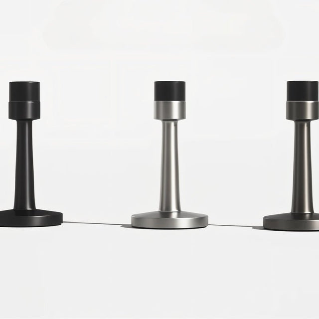 "Collection of sleek, cylindrical zinc-alloy door stops with sturdy bases and extended arms in various modern finishes, designed to prevent doors from hitting walls."