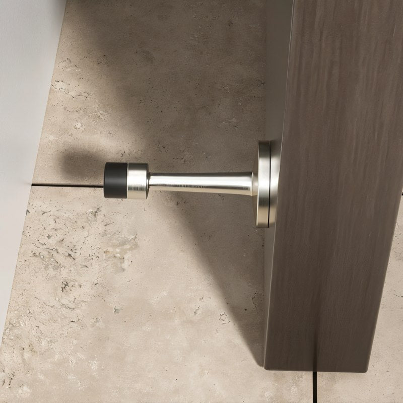 "Sleek, cylindrical door stop with extended arm, wall-mounted to prevent a door from hitting and damaging the wall in a modern interior."