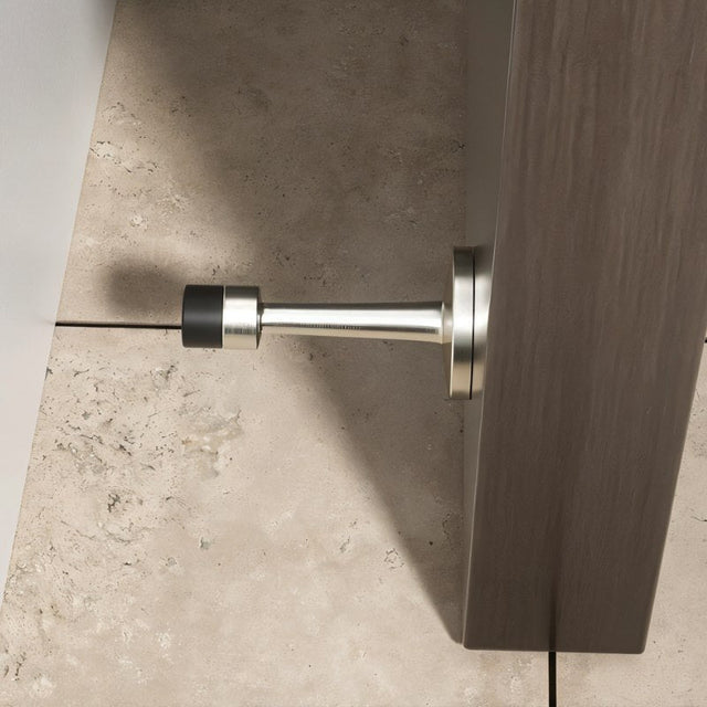 "Sleek, cylindrical door stop with extended arm, wall-mounted to prevent a door from hitting and damaging the wall in a modern interior."