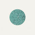 Teal terrazzo circle with speckled black and white aggregate on cream background.