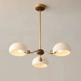 "A modern three-light chandelier with dome-shaped glass shades and a copper frame."