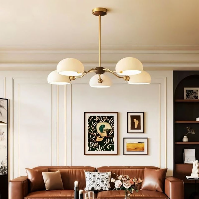 "A five-light chandelier with dome-shaped glass shades hangs above a dining table in a modern dining room."