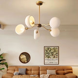 "A modern chandelier with dome-shaped glass shades hangs above a living room sofa, illuminating the space."