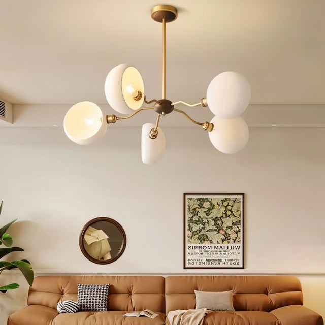 "A modern chandelier with dome-shaped glass shades hangs above a living room sofa, illuminating the space."