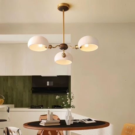 "A three-light chandelier with dome-shaped glass shades hangs above a kitchen table, providing ambient lighting."
