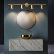 "Modern brass bathroom vanity lighting with four adjustable heads mounted on a circular base above a round mirror in a contemporary bathroom."