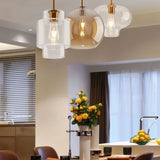 "Three pendant lights with different shaped glass shades hanging above a dining table with flowers."