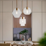 "Three clear glass pendant lights with different shapes hanging above a dining table."