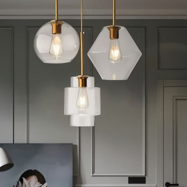"Three modern pendant lights with clear glass shades in different shapes, hanging together."