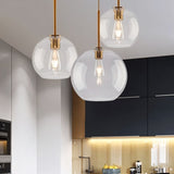 "Three clear glass sphere pendant lights hanging above a kitchen counter."