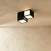Modern geometric ceiling light fixture with black frames, white panels, and brass accents on neutral background