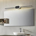 Modern black LED vanity light fixture mounted above a bathroom mirror with white sink and storage shelf.