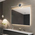 Modern chrome LED vanity lamp with circular center detail mounted above illuminated bathroom mirror.