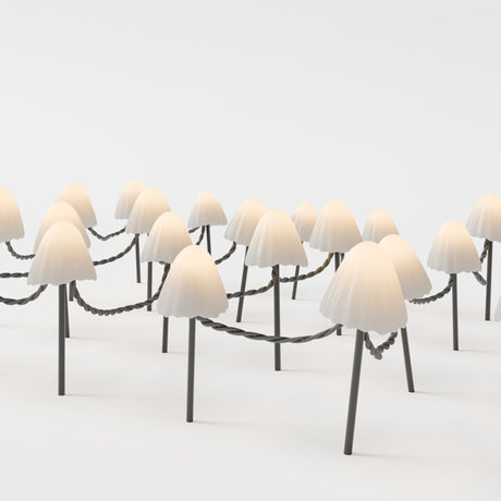 Multiple cream-colored mushroom-shaped outdoor lamps with dark stems connected by draped cords in a snowy white setting.