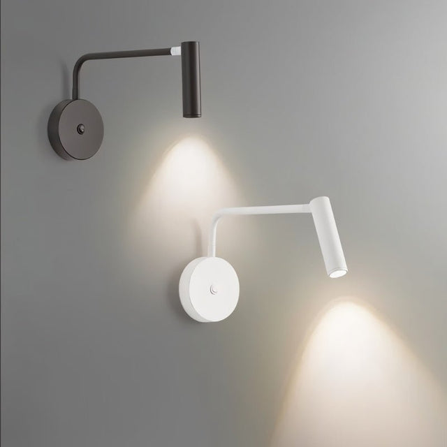 "Two wall lamps, one black and one white, with pivoting arms and cylindrical heads, lit up on a gray wall."