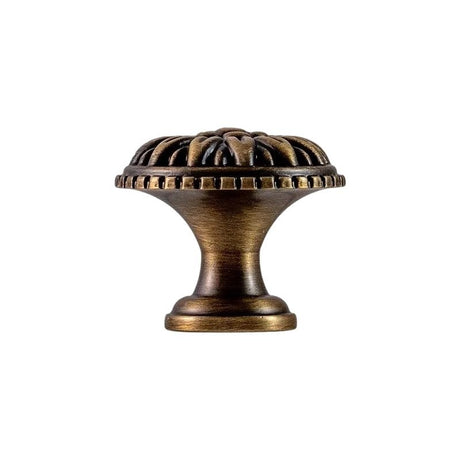 "Antique brass floral knob with raised petal detailing, isolated on a white background."
