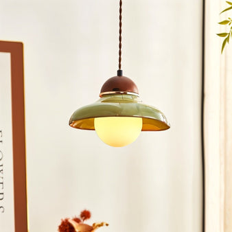 "Handcrafted pendant light with a curved ceramic shade and wooden top, illuminated and showcasing its vintage-modern style."