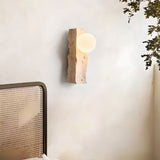 "travertine wall lamp with frosted glass globe mounted on a bedroom wall"