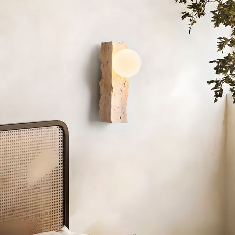 "travertine wall lamp with frosted glass globe mounted on a bedroom wall"