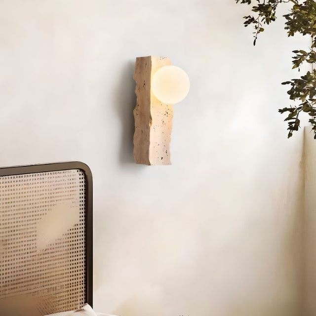 "travertine wall lamp with frosted glass globe mounted on a bedroom wall"