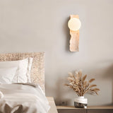 "travertine wall lamp with frosted glass globe in a cozy bedroom setting"