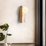 "Minimalist wall lamp with a raw travertine base and frosted glass globe, mounted on a neutral-toned wall"