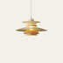 Pendant light with stacked brass and wood disc shades in warm gold tones hanging against a neutral background.