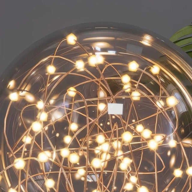 "A close-up view of a clear glass sphere with warm fairy lights inside."