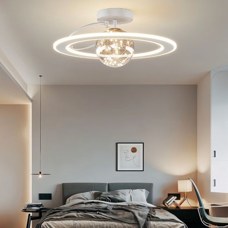 "A white ceiling light with two rings and a central glass sphere with fairy lights, installed in a bedroom with a gray bed and artwork."