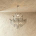 Gold tiered chandelier with cascading metal chains against dark wall in modern living room setting.