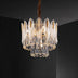 Round crystal chandelier with gold-toned metal frame and tiered glass leaf pendants, illuminated against dark ceiling.