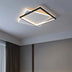 Modern square ceiling light with black frame and warm white LED glow mounted on gray ceiling in bedroom.