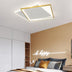 Modern square LED ceiling light with gold frame and integrated lighting over a contemporary bedroom with tan accent wall.