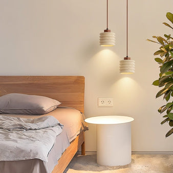 "Two travertine pendant lights with a ribbed design hanging over a bed."