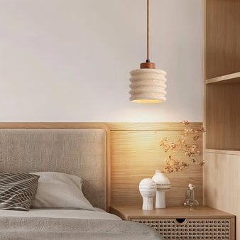 "A travertine pendant light with a ribbed design in a bedroom setting."