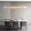 "A linear chandelier with sculpted glass petals and an iron frame in a dining room."