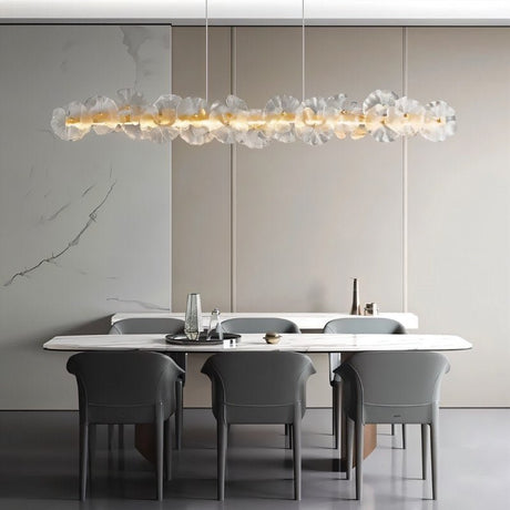 "A linear chandelier with sculpted glass petals and an iron frame in a dining room."