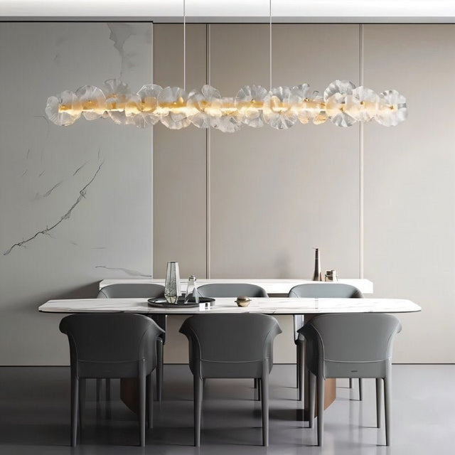 "A linear chandelier with sculpted glass petals and an iron frame in a dining room."