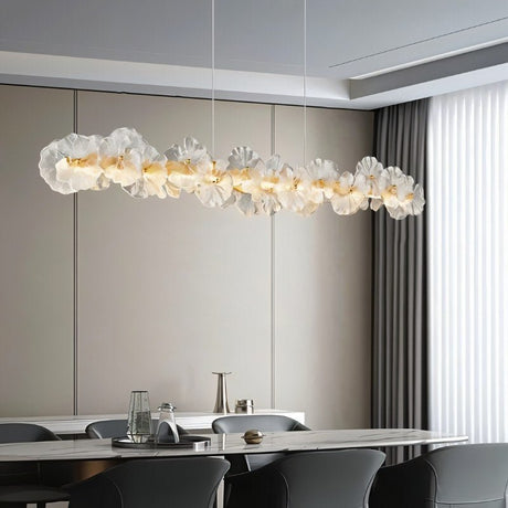 "A linear chandelier with sculpted glass petals and an iron frame above a dining table."