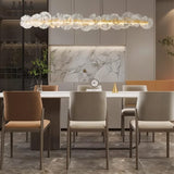 "A linear chandelier with sculpted glass petals and an iron frame in a modern dining room."