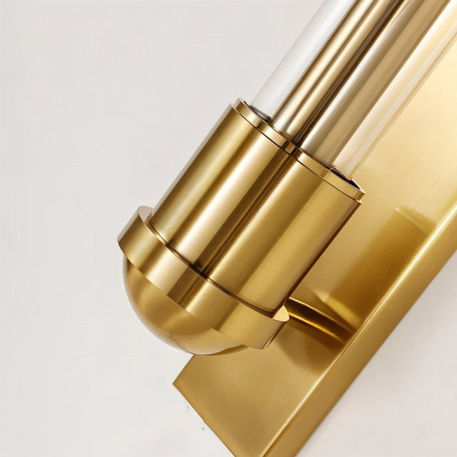 "Close-up of a modern brass wall lamp with a rectangular base and a cylindrical glass shade, showcasing the details and craftsmanship."