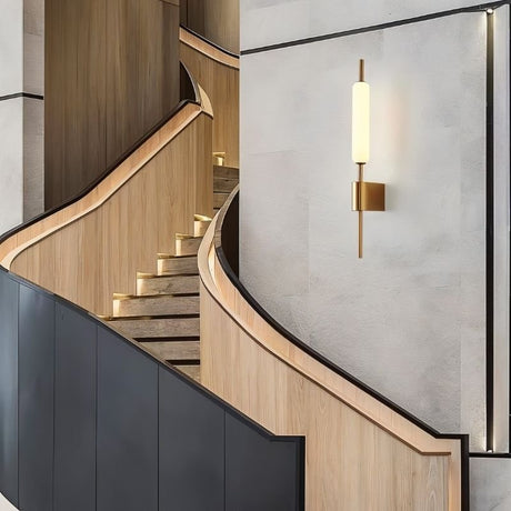 "Modern wall lamp with a cylindrical glass diffuser and iron frame illuminating a contemporary staircase."